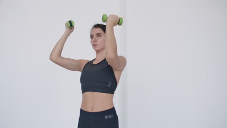 basic-exercise-for-the-deltoid-muscle:-A-young-Caucasian-woman-lifts-dumbbells-for-arm-and-shoulder-exercises.-Lift-dumbbells-over-your-head